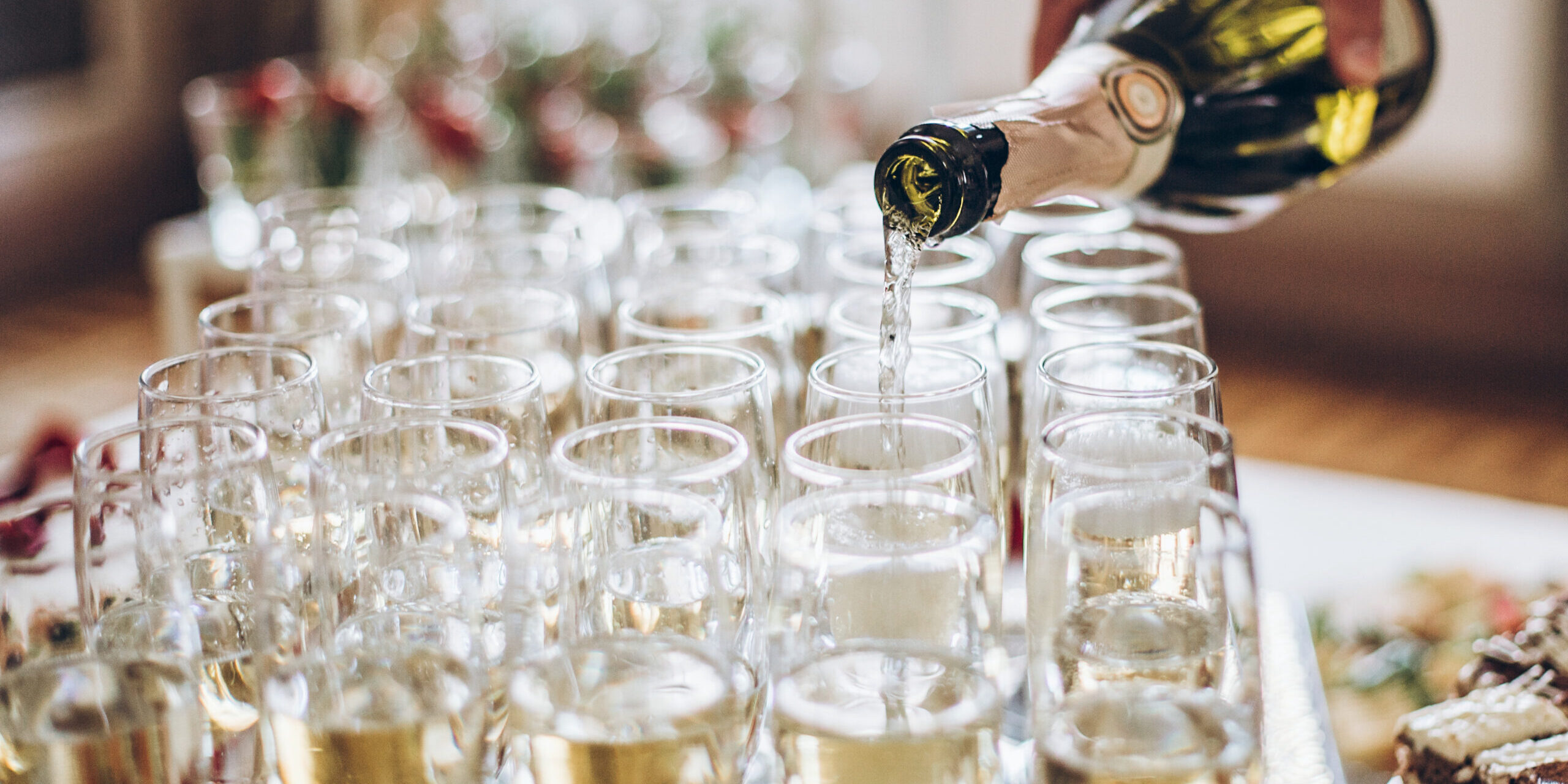 champagne golden glasses. waiter pouring champagne in stylish glasses at luxury wedding reception. rich celebration. expensive catering and service at feast. new year and christmas